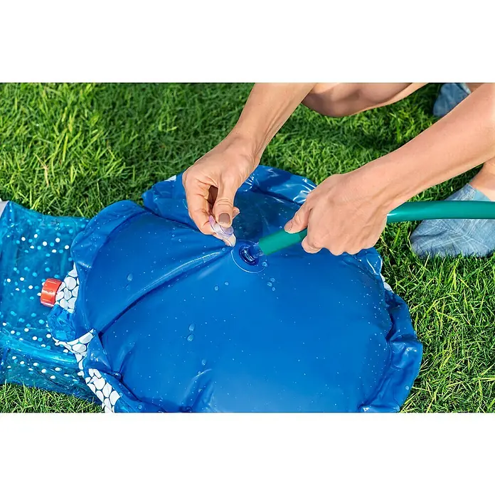 Bestway Boxsack UFO mit Wassersprinkler - Blau - Hände füllen ein blaues aufblasbares Planschbecken mit Wasser aus einem grünen Schlauch.