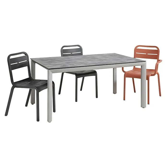 Grosfillex Gartentisch Greggia - L x B x H: 160 x 95 x 74,5 cm, Aluminium, HPL, Grau - Terrassen-Essgruppe mit grauem Tisch und drei Stühlen (zwei dunkelgrau, einer korall).