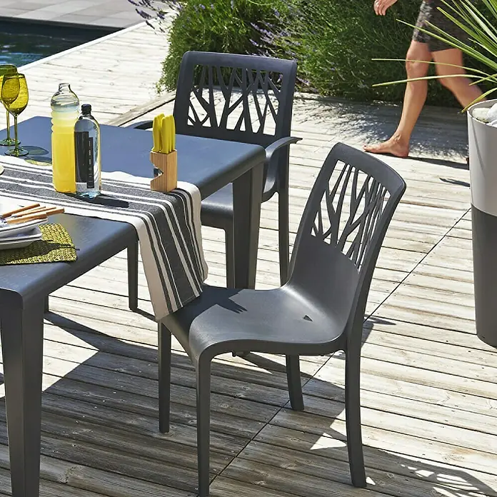 Grosfillex Stapelstuhl Set Vegetal - 4 Stk., Polypropylen, Anthrazit, B x T x H: 60 x 58 x 88 cm - Dunkelgraue Outdoor-Esstischgruppe mit Stühlen im Baum-Muster auf Holzterrasse.