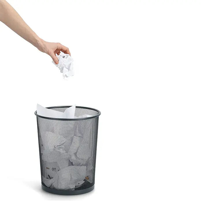 Zeller Present Papierkorb Mesh - Ø x H: 29,5 x 35 cm, Metall, Anthrazit - Eine Hand wirft zerknülltes Papier in einen schwarzen Maschenpapierkorb, der teilweise mit Papier gefüllt ist.