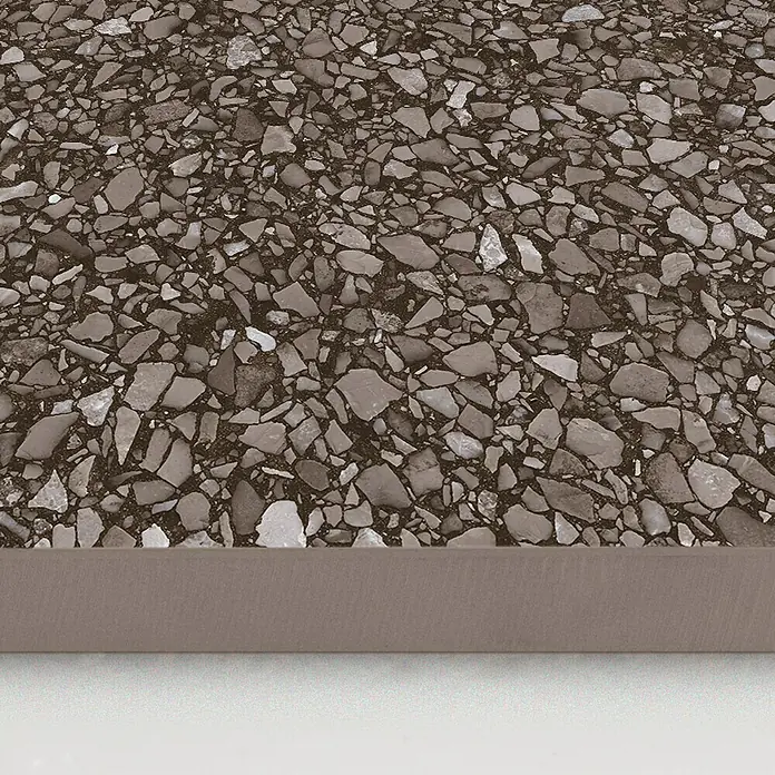 DryTile Feinsteinzeugfliese Terrazzo Red - 60 x 60 cm, Rot, Matt - Nahaufnahme einer braunen Terrazzo-Fliese mit unregelmäßigen grauen und weißen Steinsplittern und einer glatten braunen Kante.