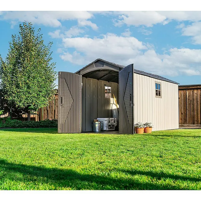Lifetime Gerätehaus Utah - Kunststoff, Grau, Außenmaß inkl. Dachüberstand (B x T): 206 x 427 cm - Beiger und dunkelbrauner Geräteschuppen mit geöffneten Türen, zeigt Schubkarre und Kühlbox, in einem sonnigen Garten.