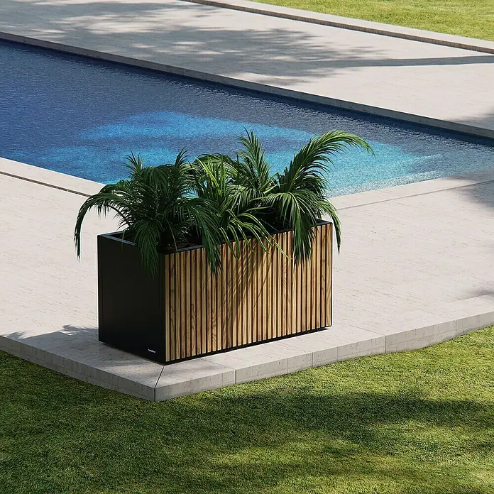 Herstera Garden Pflanzkasten Deco Planter - Außenmaß (L x B x H): 100 x 50 x 50 cm, Holz, Braun/Schwarz - Ein großer schwarzer Pflanzkübel mit Holzlamellen und üppigen Grünpflanzen, neben einem Pool auf einer Terrasse.