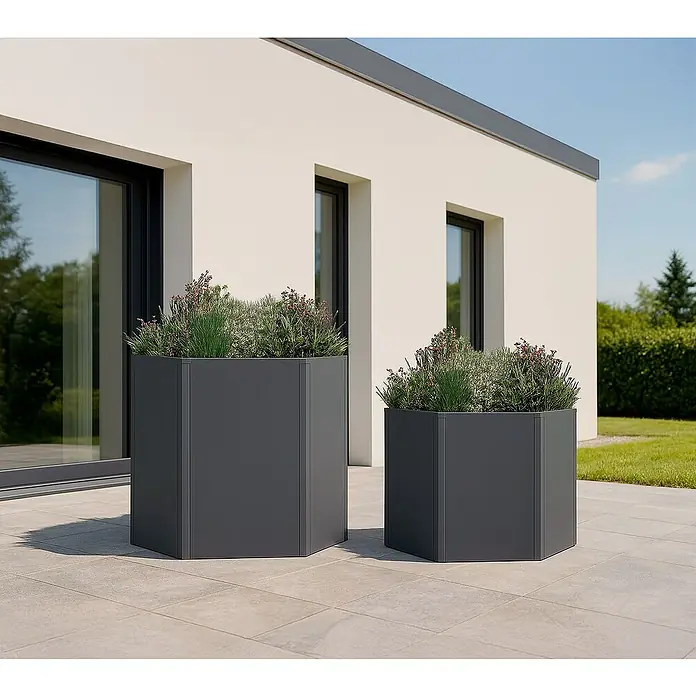Westmann Hochbeet Varia Set - Metall, Grau - Zwei dunkelgraue sechseckige Metallpflanzgefäße, ein großes und ein kleines, bepflanzt, auf einer Terrasse neben einem modernen Gebäude.