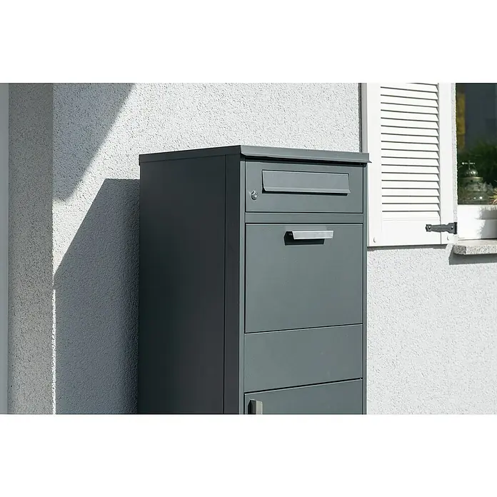 Westmann Paketbox Pedro - Höhe: 112 cm, Grau, Stahl - Dunkelgrauer Brief- und Paketkasten für den Außenbereich, neben einem Haus stehend.