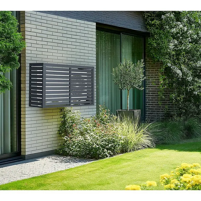 Westmann Verkleidung Boxa M - Ausführungseigenschaft: L 140 x B 56 x H 97 cm, Anthrazit - Dunkelgraue Lamellen-Klimaanlagenabdeckung an einer hellen Ziegelhauswand, die das Gerät in die moderne Außenansicht integriert.