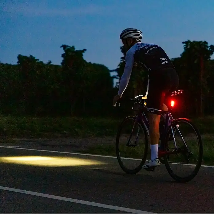 Sigma Dynamo-LED-Rücklicht Blaze - Ohne Batterien - Radfahrer auf einem Rennrad in der Dämmerung, beleuchtet von aktiven Vorder- und Rücklichtern zur Sicherheit.