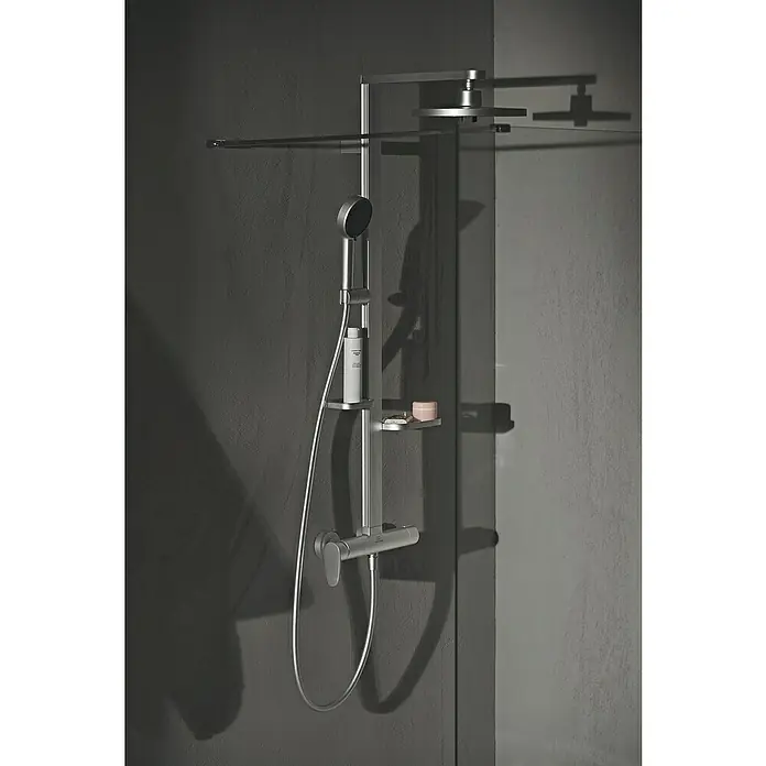 Ideal Standard Alu+ Duschsystem Ceraflow BD584SI - Lochabstand: 60 cm, Anzahl Strahlarten: 2 Stk., Silber, Form Kopfbrause: Rund - Elegantes silbernes Duschsystem mit Hand- und Regenduschköpfen, Ablage, an dunkler Wand neben Glasabtrennung.