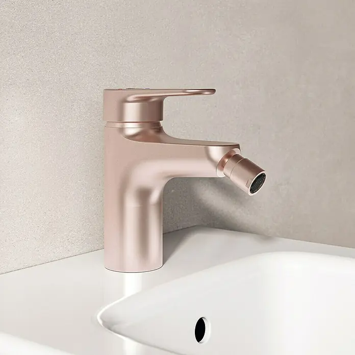 Ideal Standard Alu+ Bidetarmatur - Höhe: 140 mm, Rosé - Roségoldener Bidetmischer mit integrierter Brause, auf einem weißen Waschbecken montiert.