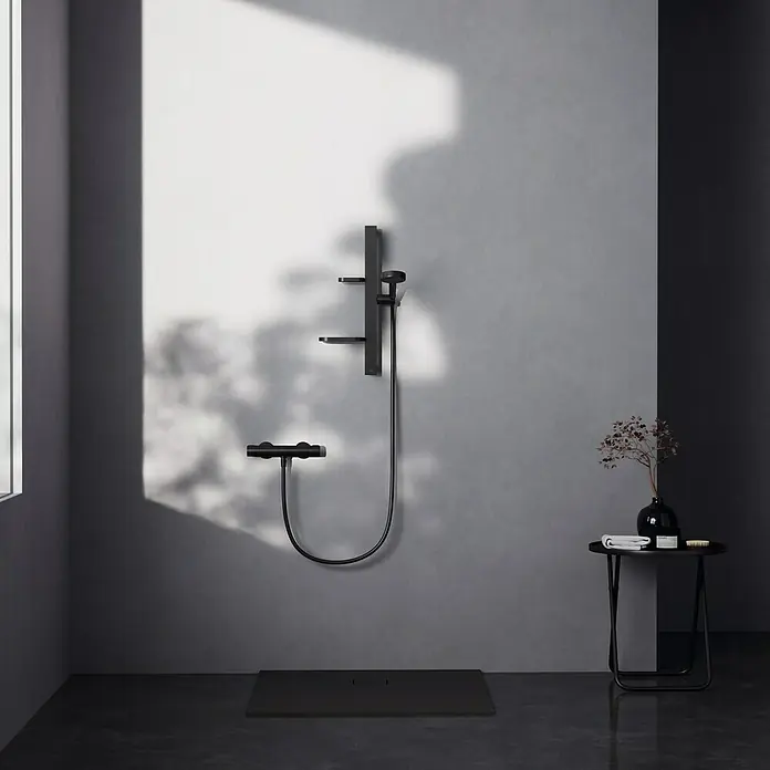 Ideal Standard Alu+ Brausegarnitur Ceratherm - Lochabstand: 40 cm - 50 cm, Art Strahl: SilkRain, Rain, Schwarz - Matt-schwarzes Duschsystem mit Handbrause, Mischer und Schlauch, installiert über einer passenden schwarzen Duschwanne.