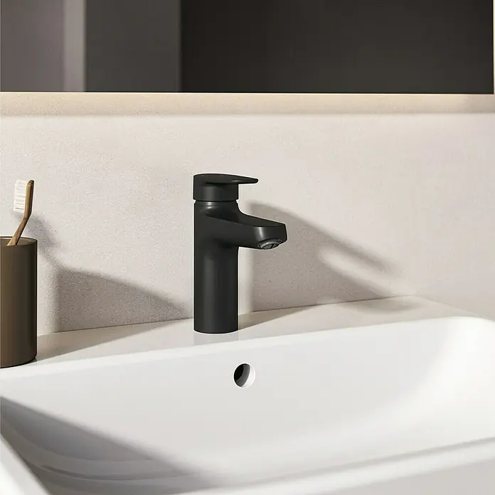 Ideal Standard Alu+ Waschtischarmatur - Höhe: 160 cm, Schwarz - Mattschwarzer Wasserhahn in einem weißen Waschbecken, daneben eine Zahnbürste und ein Halter.