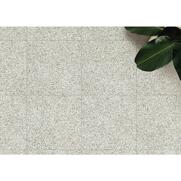 DryTile Feinsteinzeugfliese Terrazzo Ivory - 60 x 60 cm, Grau, Matt - Hellgraue Terrazzobodenfliesen mit einer Pflanze im Topf in der Ecke, von oben gesehen.