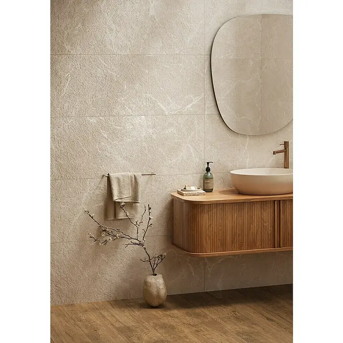 Wandfliese Benora - 39,8 x 119,8 cm, Ivory Struktur, Matt - Modernes Badezimmer mit beigefarbenen strukturierten Wandfliesen, einem geriffelten Holzwaschtisch, einem weißen Aufsatzwaschbecken und einem großem ovalem Spiegel.