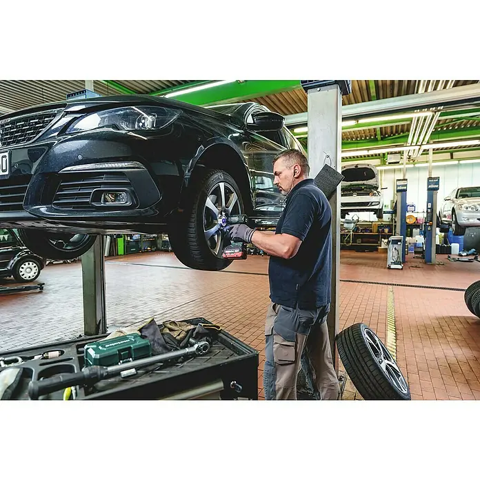 Metabo Akku-Schlagschrauber SSW 18 LTX 550 BL - 18 V, Ohne Akku, Max. Schlagzahl: 3.600 /min - Ein Mechaniker verwendet einen grün-schwarzen Metabo Schlagschrauber, um einen Autoreifen an einer Hebebühne in einer Werkstatt zu wechseln.