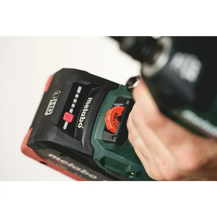 Metabo Akku-Schlagschrauber SSW 18 LTX 550 BL - 18 V, Ohne Akku, Max. Schlagzahl: 3.600 /min - Nahaufnahme einer Hand, die ein rotes Einstellrad an einem schwarz-grünen Metabo-Elektrowerkzeug mit rotem Akku und Ladestandsanzeige betätigt.