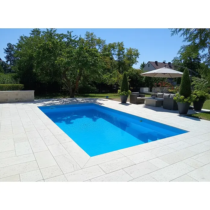 Mountfield Bausatz-Pool - L x B x H: 490 x 350 x 140 cm, 17,59 m³, Blau - Heller Poolbereich mit hellen Travertinfliesen und Gartenmöbeln, in einem sonnigen Garten gelegen.