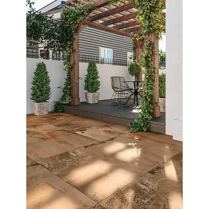 Terrassenfliese Metallic 2.0 - 60 x 120 x 2 cm, Kupfer, Matt - Rustikale braune und beige Terrassenfliesen, auf einer geräumigen Terrasse unter einer Pergola verlegt.