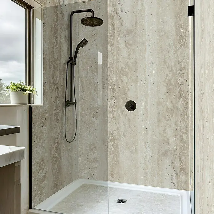 Dumawall+ Revestimiento de pared de PVC Ember - 260 x 90 cm, Beige - Ducha moderna con mampara de cristal transparente, grifería de bronce y paredes claras efecto travertino.