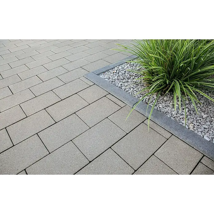EHL Pflasterstein Cortona Flair - 40 x 20 x 8 cm, Grau, Beton - Graue rechteckige Pflastersteine diagonal verlegt, grenzend an ein Pflanzenbeet mit dunkler Einfassung und grünen Pflanzen.