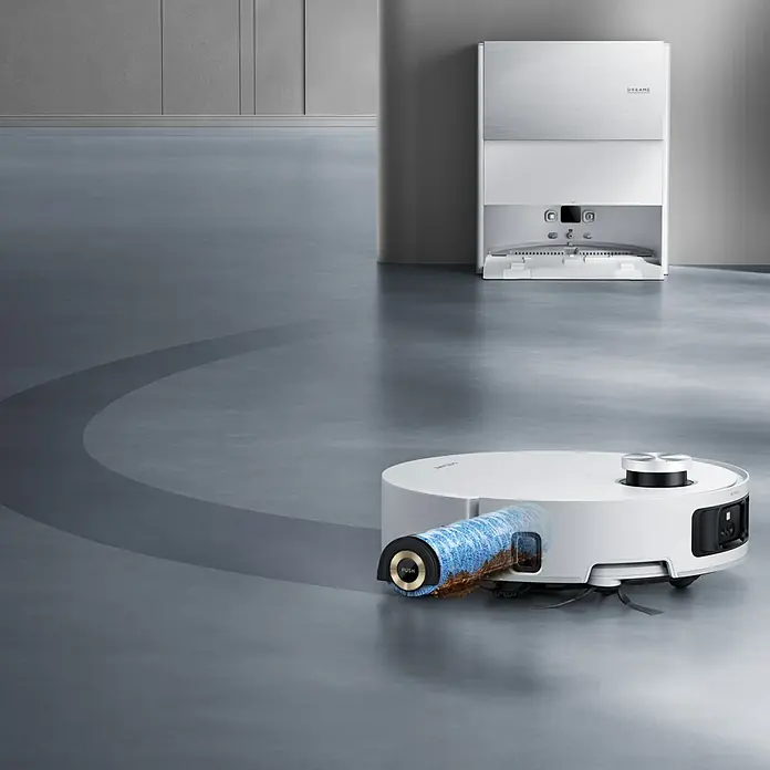 Dreame Saugwischroboter Aqua10 - Saugkraft: 30.000 Pa, Akkulaufzeit: 200 min, Fassungsvermögen Roboter: 220 ml - Weißer Saugroboter mit sichtbarer blauer Bürstenrolle, reinigt grauen Boden, nahe seiner weißen Ladestation.