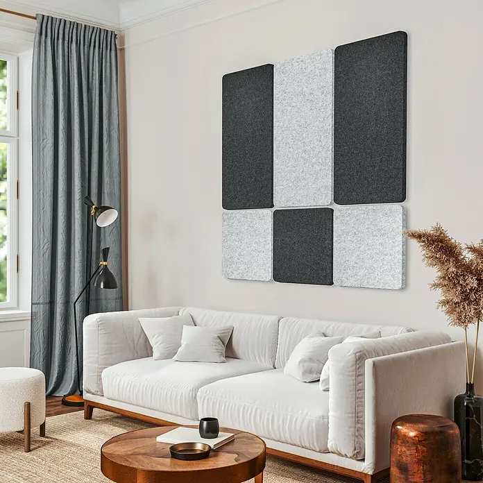 Lautloz Akustikpaneel Shapez - Hellgrau, L x B x S: 45 x 45 x 2,4 cm - Filz-Akustikpaneele in Dunkel- und Hellgrau, schachbrettartig an einer Wohnzimmerwand über einem Sofa angeordnet.