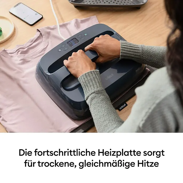 Cricut Transferpresse EasyPress SE + Hitzeschutzmatte - 25 x 30 cm, Passend für: Bügelfolien - Eine Person bedient eine graue Cricut Heizpresse auf einem pinken T-Shirt.