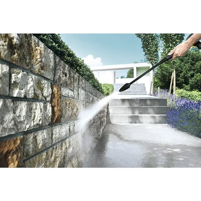 Kärcher Dreckfräse DB 180 - Passend für: Kärcher Hochdruckreiniger K7 - Hand hält schwarze Hochdruckreinigerlanze, reinigt Steinmauer mit Wasser.