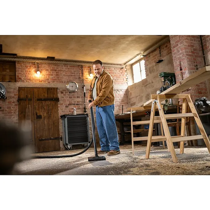 Kärcher Elektro-Nass- & Trockensauger WD 7 Control P S 30/6/35/T - Behältervolumen: 30 l, 1.400 W - Mann reinigt Sägespäne vom Werkstattboden mit einem schwarzen Staubsauger.