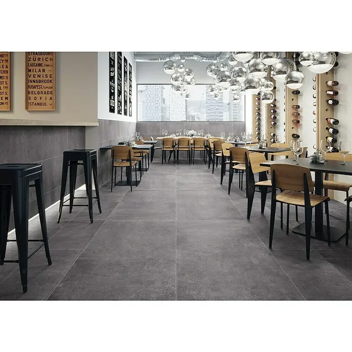 Feinsteinzeugfliese Savanna - 59,7 x 119,7 cm, Anthrazit, Matt - Dunkelgraue, großformatige Bodenfliesen mit dezenter Textur in einem Restaurantambiente.