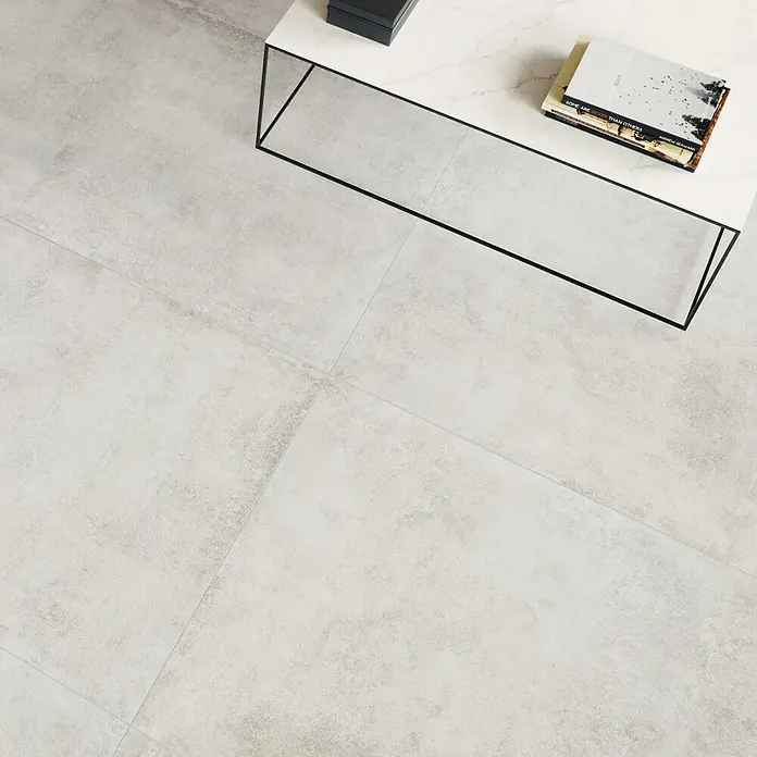 Feinsteinzeugfliese Savanna - 59,7 x 119,7 cm, Gris, Matt - Helle, strukturierte Bodenfliesen in Grau in einem modernen Wohnraum mit Couchtisch.