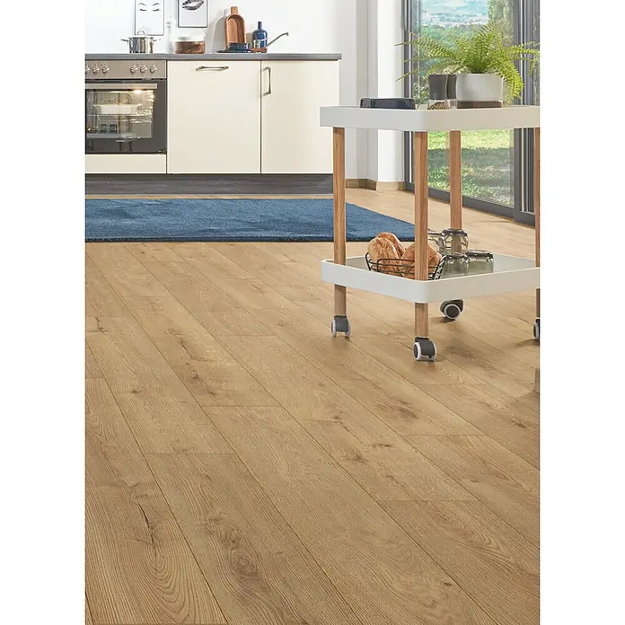 LOGOCLIC Aquaprotect Smart Silent Laminat - Pandora, Landhausdiele, 1.288 x 195 x 7 mm - Hellbrauner Laminatboden in Holzoptik füllt eine moderne Küche, mit blauem Teppich und Servierwagen.
