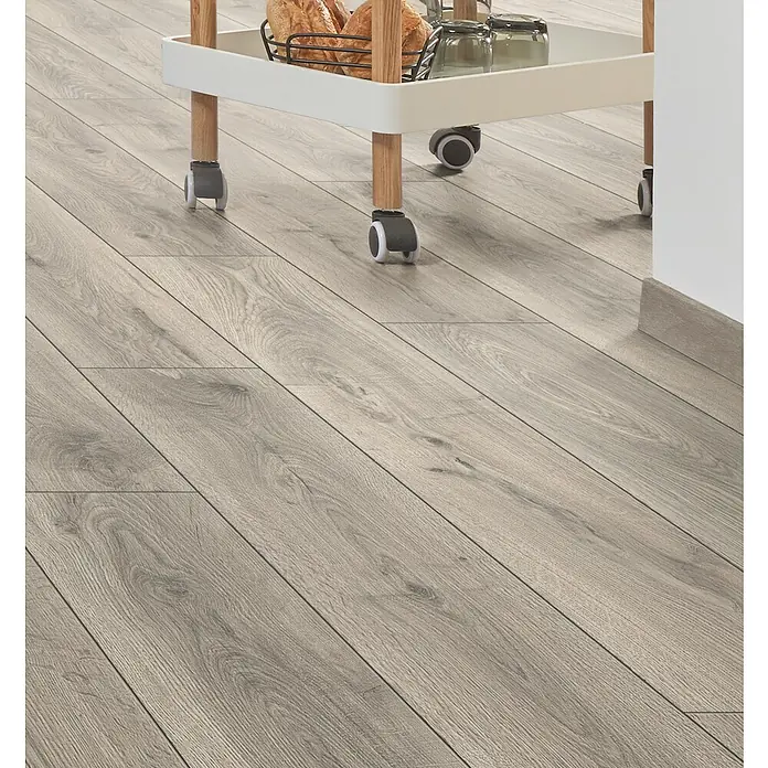 LOGOCLIC Aquaprotect Smart Silent Laminat - Lombok Oak, Landhausdiele, 1.288 x 195 x 7 mm - Helles grau Holzoptik-Laminatboden unter einem Servierwagen.