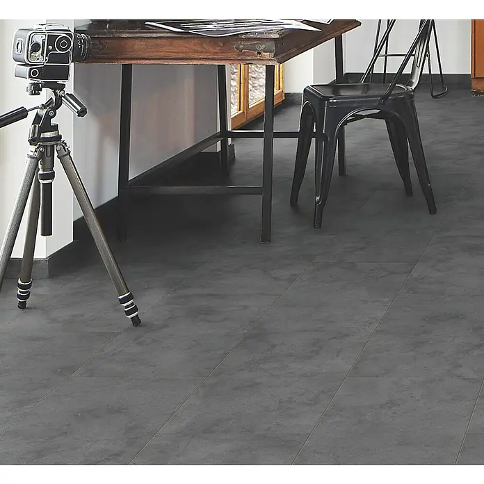 LOGOCLIC Ceramico Laminat - Dark Slate, Fliese, 638 x 330 x 8 mm - Dunkelgraue Fliesen in Betonoptik bilden eine stilvolle, robuste Bodenfläche in einem Innenraum mit Tisch und Stuhl.