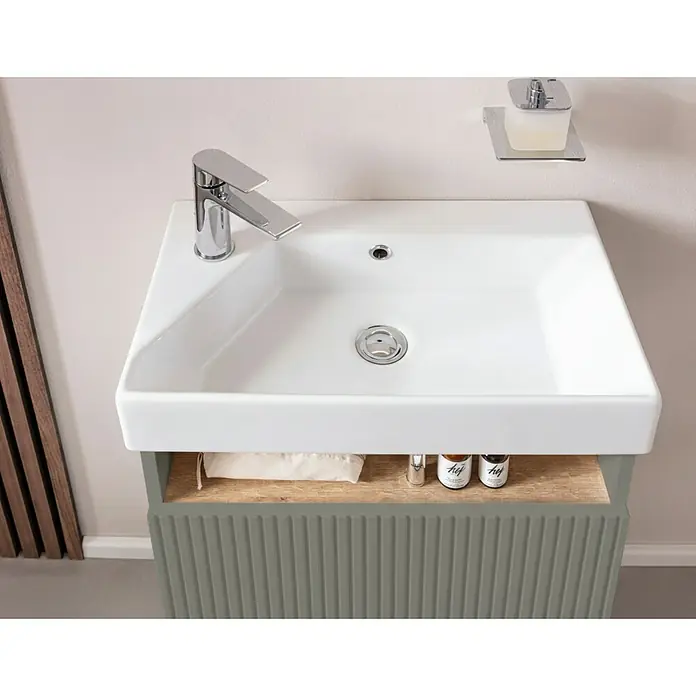Camargue Pure Badmöbel-Set - Gesamtbreite Badmöbel: 55 cm, Salbeigrün, Matt - Weißes rechteckiges Waschbecken mit Chromarmatur auf einem salbeigrünen geriffelten Waschtischunterschrank. Ein Holzregal hält kleine Flaschen.