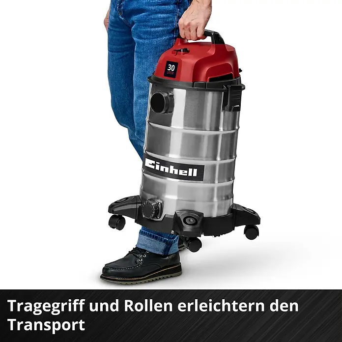Einhell Nass-Trockensauger TC-VC 3055 S - 950 W, 30 l - Person trägt einen silbernen Einhell Nass-/Trockensauger mit rotem Oberteil, der Tragegriff und Rollen für einfachen Transport zeigt.