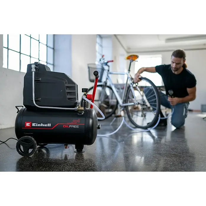 Einhell Kompressor TC-AC 190/24/8 - Max. Druck: 8 bar, 24 l, Schmierung: Ölgeschmiert - Schwarzer Einhell ölfreier Kompressor bläst einen Fahrradreifen auf, bedient von einem Mann.
