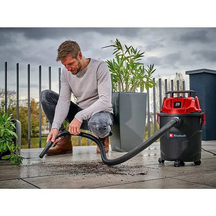Einhell Nass-Trockensauger TC-VC 2045 - 850 W, 20 l - Ein Mann saugt mit einem rot-schwarzen Einhell Nass-Trockensauger Schmutz von einer gefliesten Außenfläche.