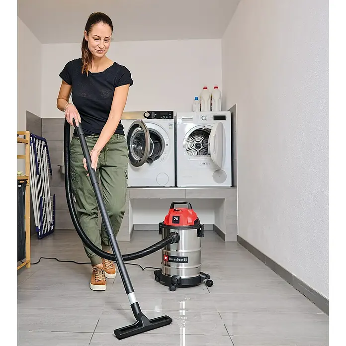 Einhell Nass-Trockensauger TC-VC 2045 S - 900 W, 20 l - Eine Frau reinigt einen nassen Boden mit einem Einhell Nass-Trocken-Sauger mit silbernem Edelstahlbehälter und rotem Oberteil.