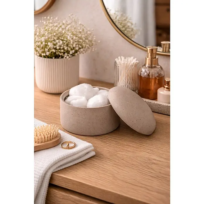 Spirella Gemma Organizador - Tierra - Recipiente color piedra con bolas de algodón blancas, tapa abierta apoyada al lado, en un tocador de baño.