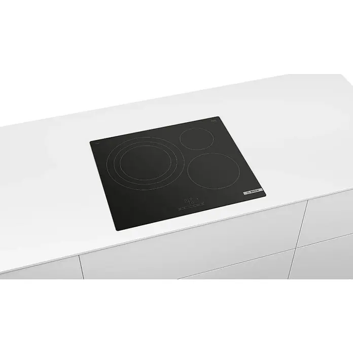 Bosch Placa de cocción PID61RBB5E - Vidrio, Número de fogones de inducción: 3 ud. - Placa de inducción Bosch negra con cuatro zonas de cocción, integrada en una encimera blanca.