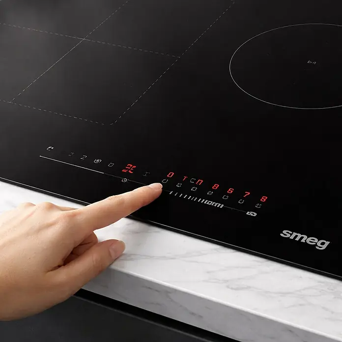 Smeg Placa de cocción SI1M4734D - Número de fogones de inducción: 3 ud. - Placa de inducción Smeg negra con controles táctiles LED rojos iluminados. Un dedo opera la elegante superficie de cristal.