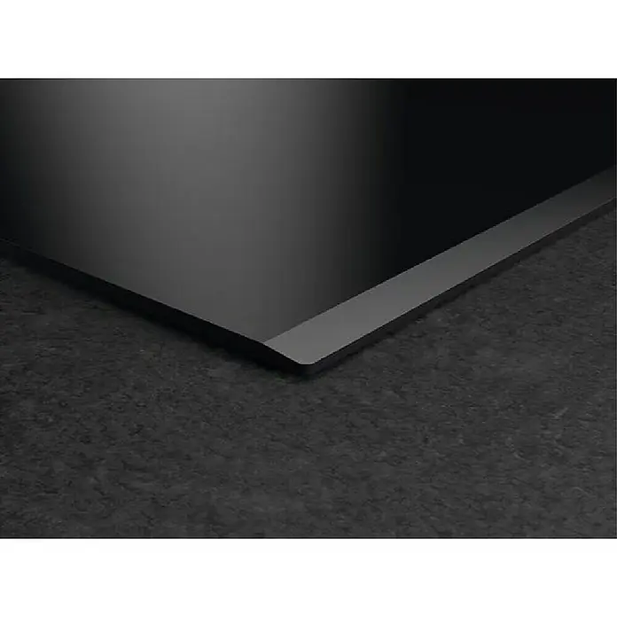 AEG Placa de cocción TO84IU0FFB - Número de fogones de inducción: 4 ud. - Placa de inducción negra moderna con marco de borde plateado, instalada sobre una encimera oscura.