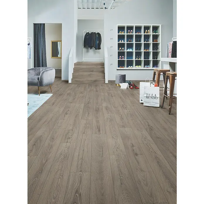 LOGOCLIC Ambienta Laminat - Venus, Landhausdiele, 1.288 x 195 x 10 mm - Taupefarbener Holzoptik-Laminatboden in einem modernen Verkaufsraum mit Treppe und Schuhregal.