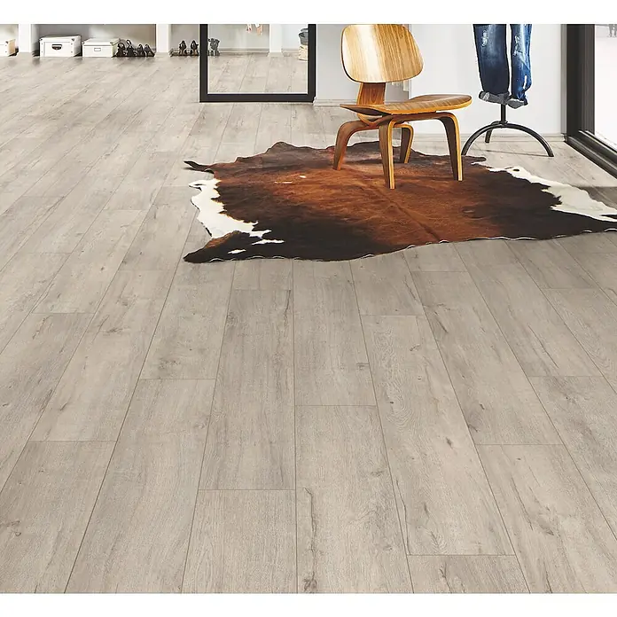 LOGOCLIC Ambienta Laminat - Aurora, Landhausdiele, 1.288 x 195 x 10 mm - Heller Holzboden mit natürlicher Maserung, in einem Raum mit einem Kuhfellteppich und einem Holzstuhl.