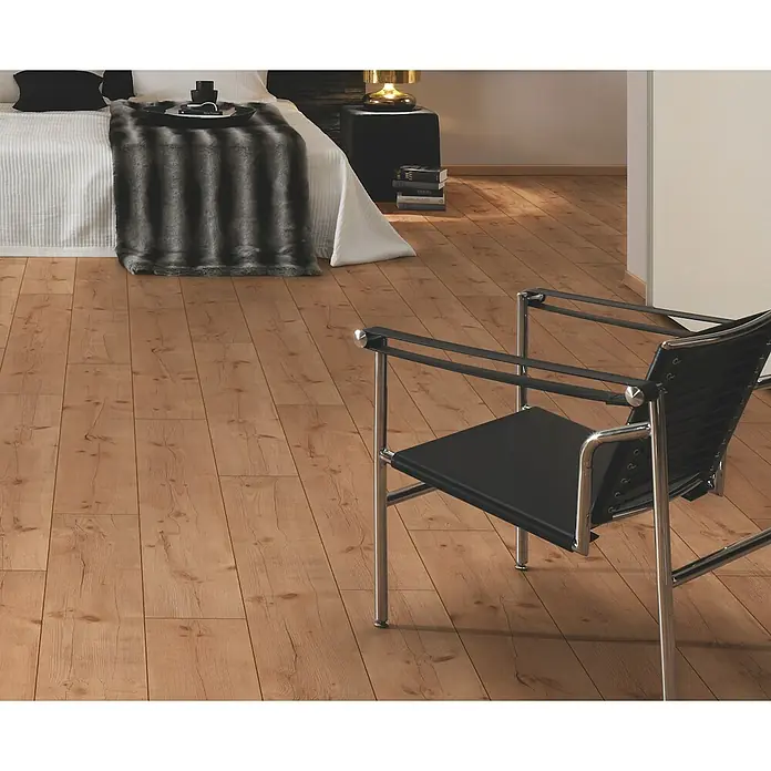 Laminat - Pinie, Landhausdiele, 1.285 x 192 x 8 mm - Helles Holzplankenparkett in einem Schlafzimmer mit modernem Chrom- und Schwarzstuhl und einem Bett mit Kunstpelzdecke.