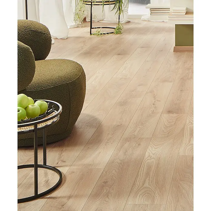 LOGOCLIC Ambienta Laminat - Honig Eiche, Landhausdiele, 1.288 x 195 x 10 mm - Heller Laminatboden in Eichenoptik in einem Wohnzimmer, unter einem grünen Sessel und Beistelltisch.