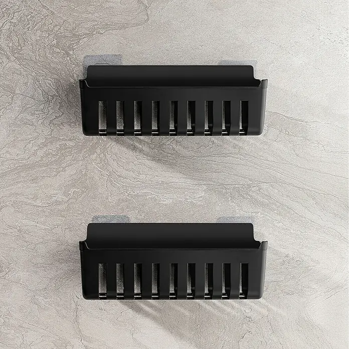 Cesta de baño Molly - 11 x 25 x 9 cm, Plástico, Negro - Dos cestas de almacenamiento de plástico negras montadas en la pared con ranuras de drenaje verticales sobre una pared de mármol.