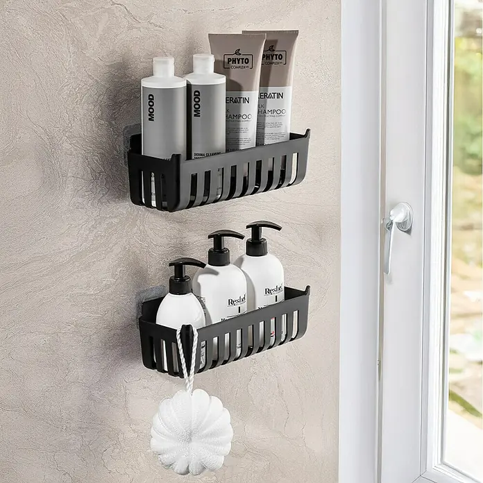 Cesta de baño Molly - 11 x 25 x 9 cm, Plástico, Negro - Dos estantes de ducha negros montados en la pared con productos de baño; el inferior incluye una esponja blanca.