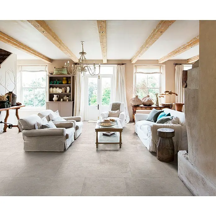 Feinsteinzeugfliese Chalk Sallow - 60 x 120 cm, Beige, Matt - Helle beige-graue Bodenfliesen in Steinoptik in einem geräumigen Wohnzimmer im Landhausstil verlegt.