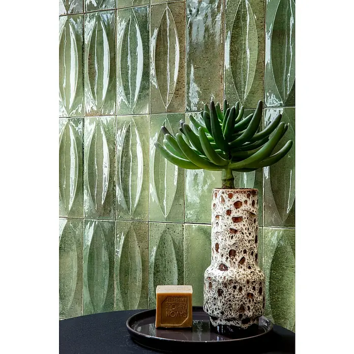Wandfliese Stella Glossy - 7,5 x 20 cm, Giada, Glänzend - Hellebraune Savon de Marseille Seife und eine grüne Sukkulente in gesprenkelter Keramikvase auf dunklem Tablett.
